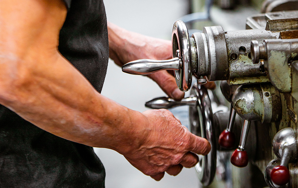 Mains d'un ouvrier ajustant les molettes et leviers d'une machine industrielle à Bourges dans le Cher 18