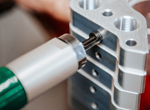 Gros plan sur un outil insérant une vis dans une pile de pièces métalliques à Bourges dans le Cher 18